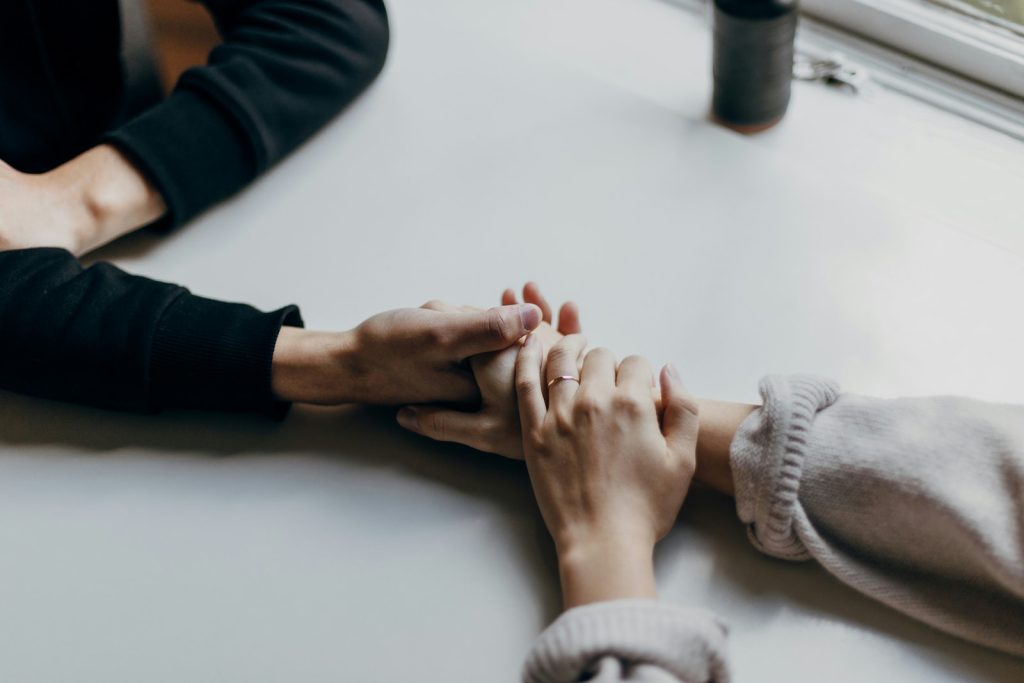 Dos personas tomándose de las manos en señal de apoyo emocional